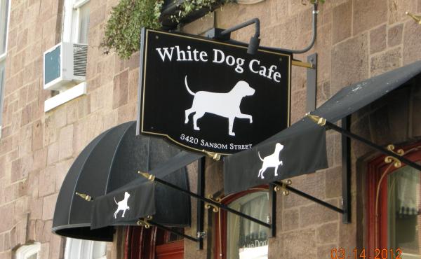Hanging sign with logo outside of White Dog Cafe 