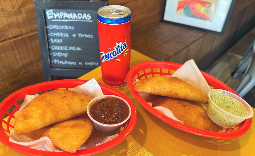 two baskets of empanadas on a table with a can of frescolita between