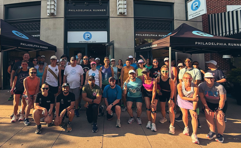 group of people posing in front of a philadelphia runner store