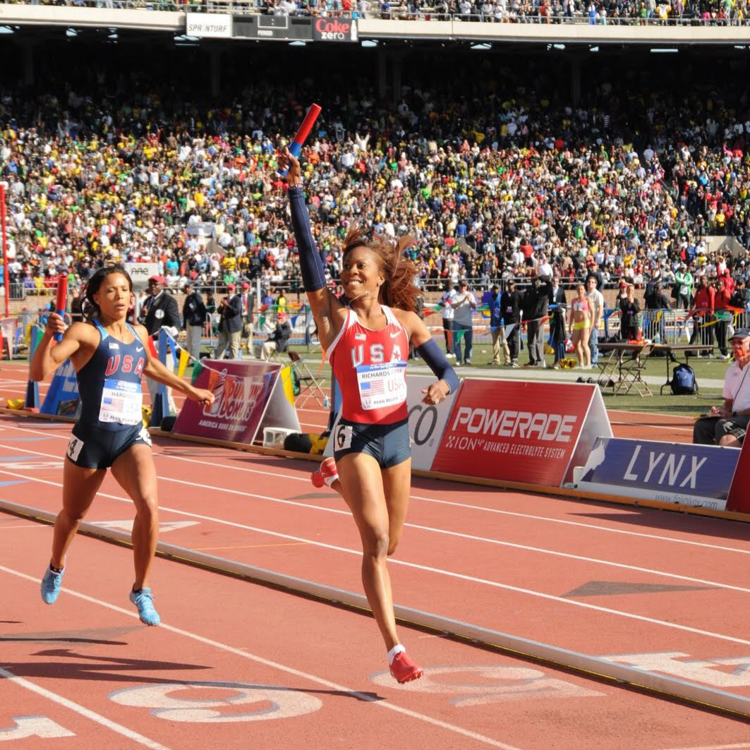 woman runner crossing finish line with hand up in celebration