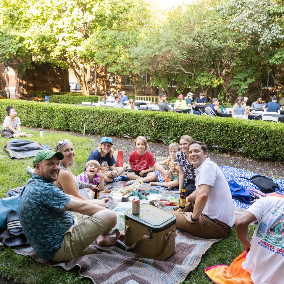July 25 Playlist family sitting on a blanket and enjoying a picnic