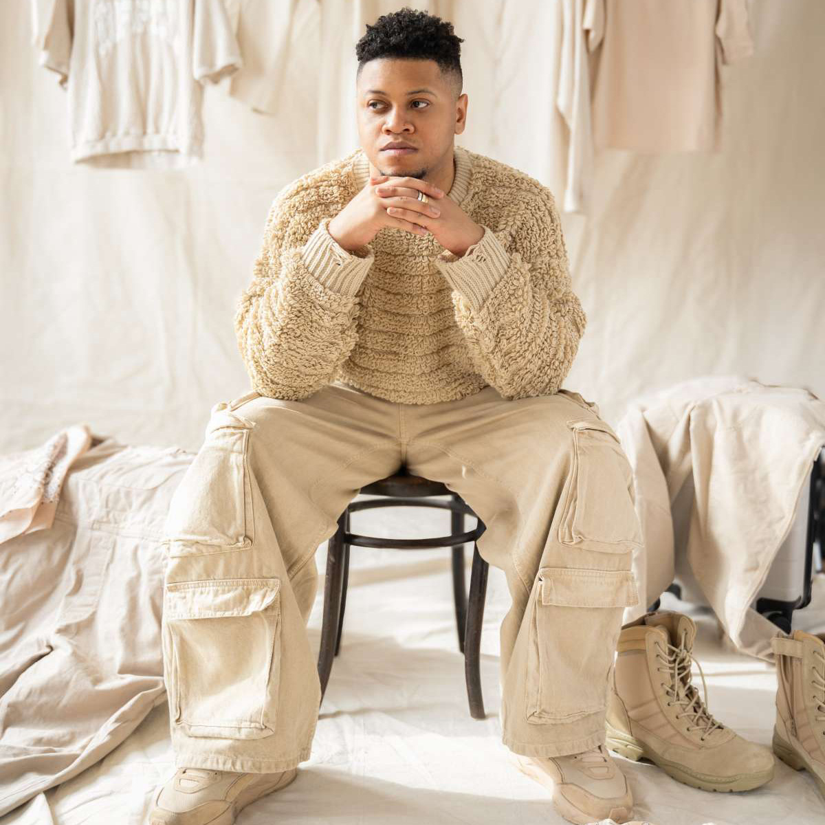 June Playlist african-american man in beige sweater and jeans sitting in front of a beige background
