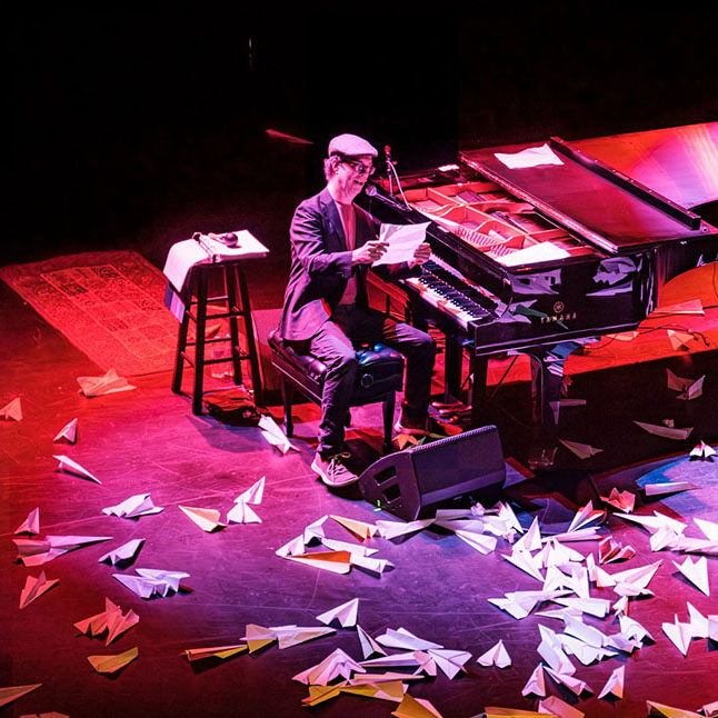 man sitting at a piano reading a paper