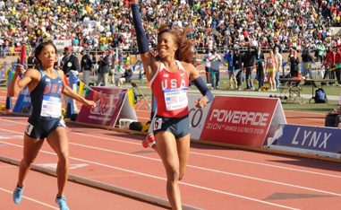 woman runner crossing the finish line with a hand up in celebration