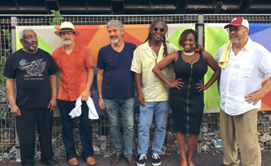 six people posing in a line for a picture outside