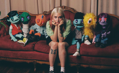 girl on couch surrounded by puppets