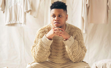 a black man in baige sweater in front of a beige background