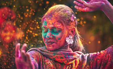 an indian woman dancing in colored dust