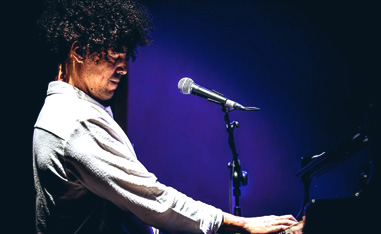 man playing piano on stage in a spotlight