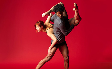 two dancers in front of a red background
