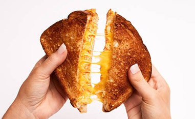 hands pulling apart a grilled cheese