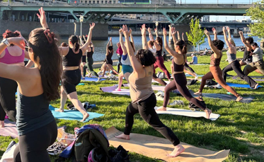 collection of people doing yoga in the park alongside a river