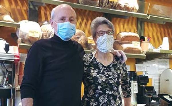 bald man and wife wearing masks in bakery