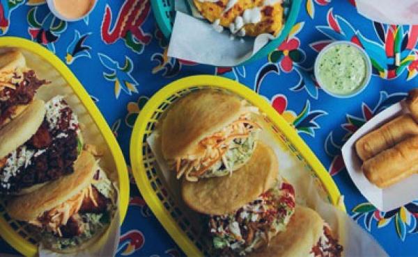 two food baskets with three arepas each and venezuelan sides