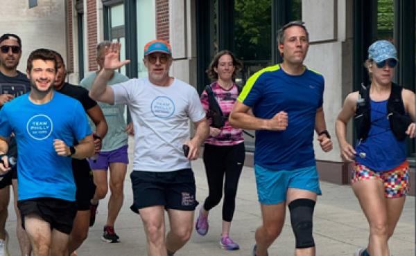 collection of runners on a city block with one waving
