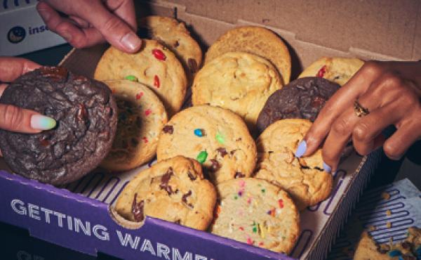 box of cookies with hands reaching for some