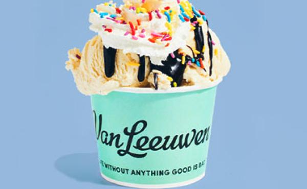 ice cream scoops in a cup with chocolate syrup, whipped cream and sprinkles