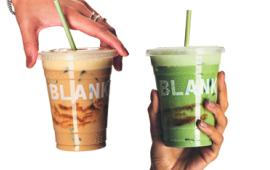 two hands holidng drinks in front of a white background. one holding the top of a coffee from above and one holding the bottom of a matcha from below, the word blank clear on each plastic cup