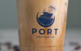 close up of a clear plastic cup filled with coffee and a logo on the cup