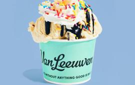 ice cream scoops in a cup with chocolate syrup, whipped cream and sprinkles